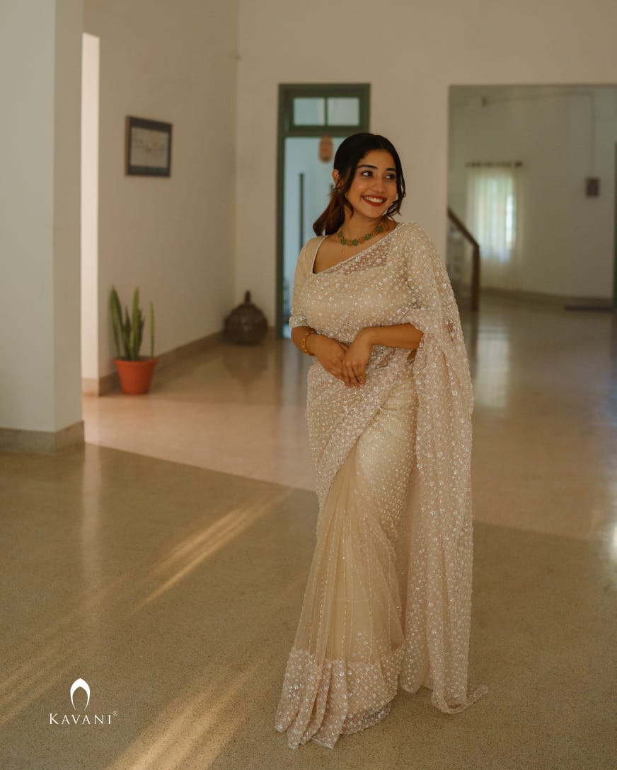 A vision of elegance and draped in majestic beige, rose, and nude net saree with intricate beaded work  that shines brightly